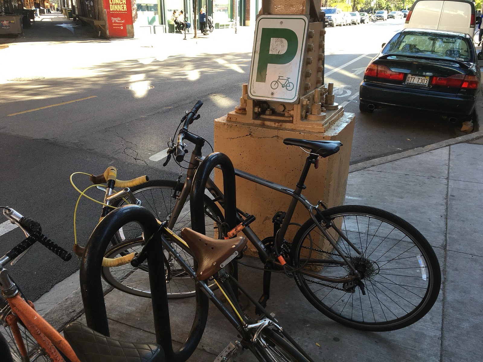 Bikes locked to wave racks beneath a bike parking sign outside Damen station