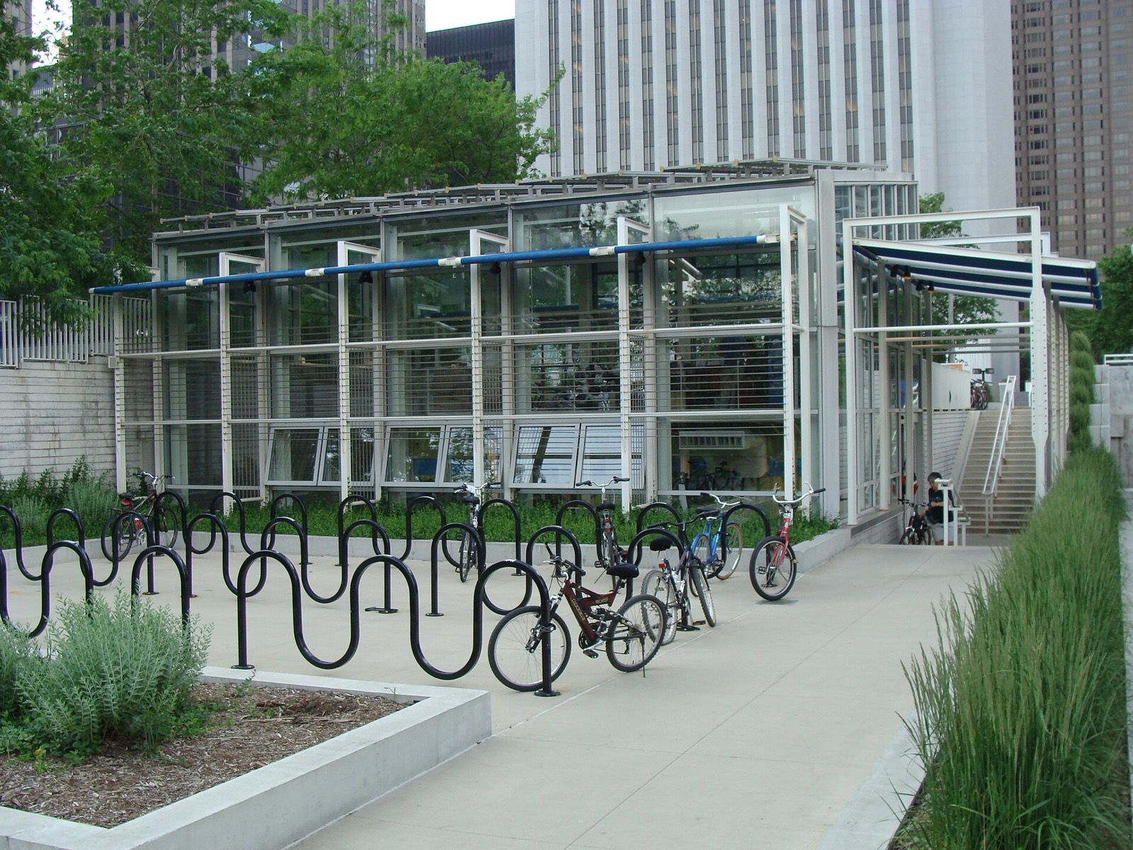 Rows of outdoor bike racks on the plaza in front of the glass bike station building