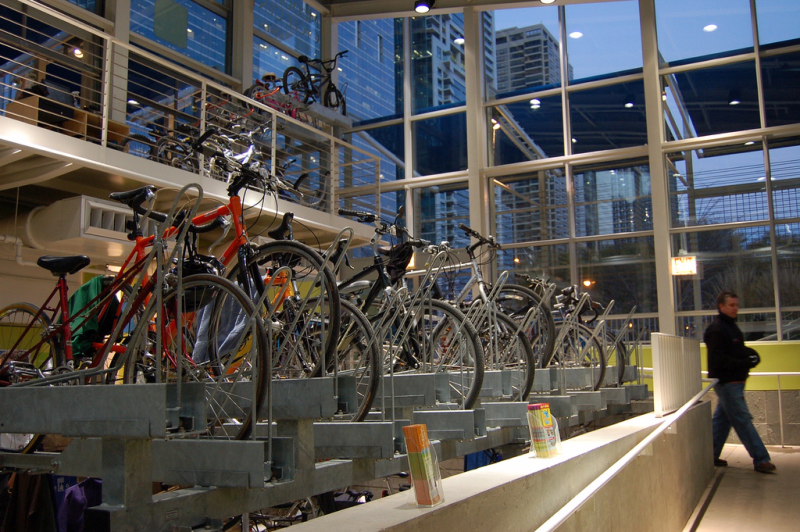 Bikes parked in indoor racks inside the heated bike station, with tall windows beyond