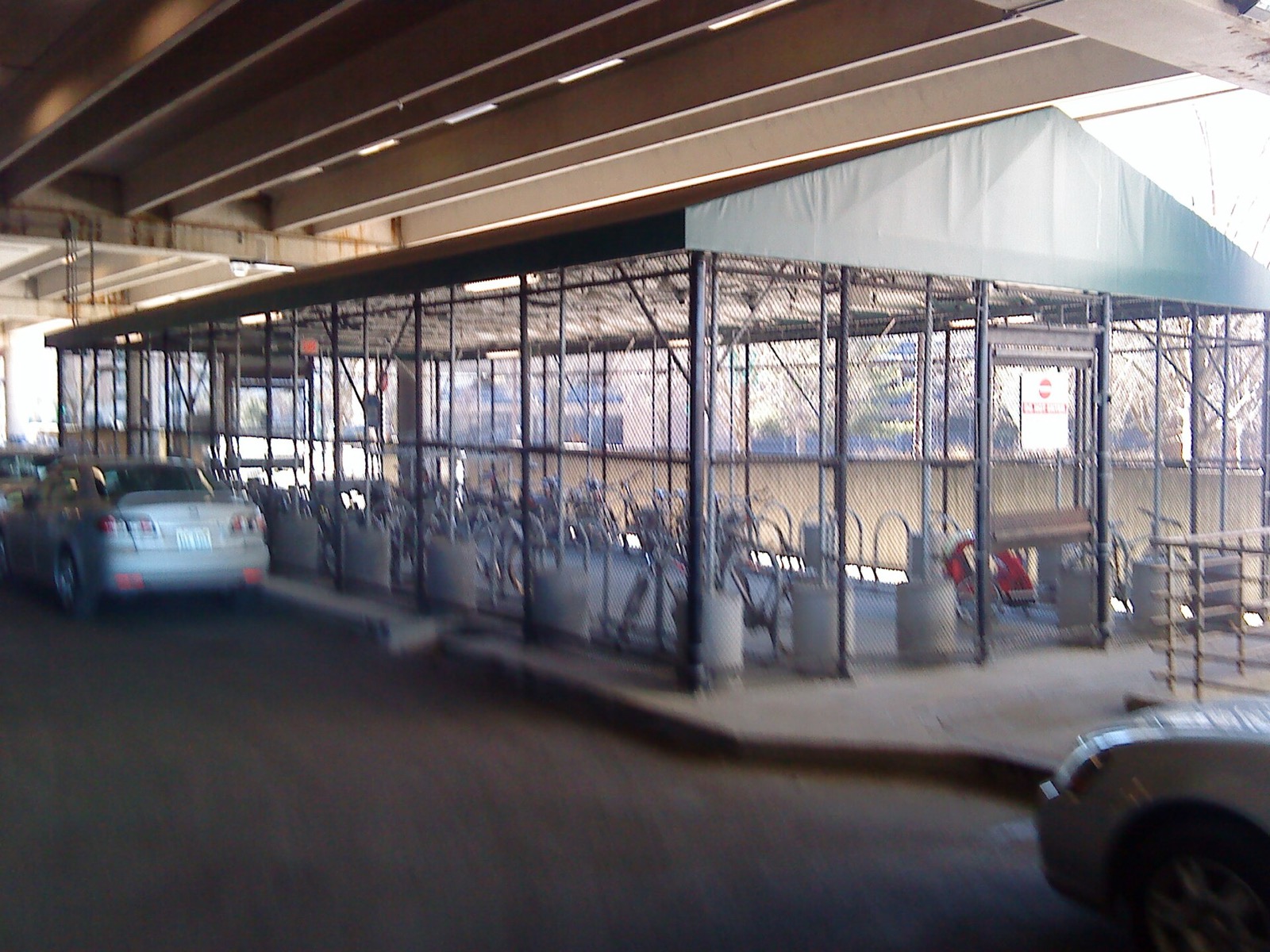 A fenced bicycle cage with racks beside the Alewife transit station