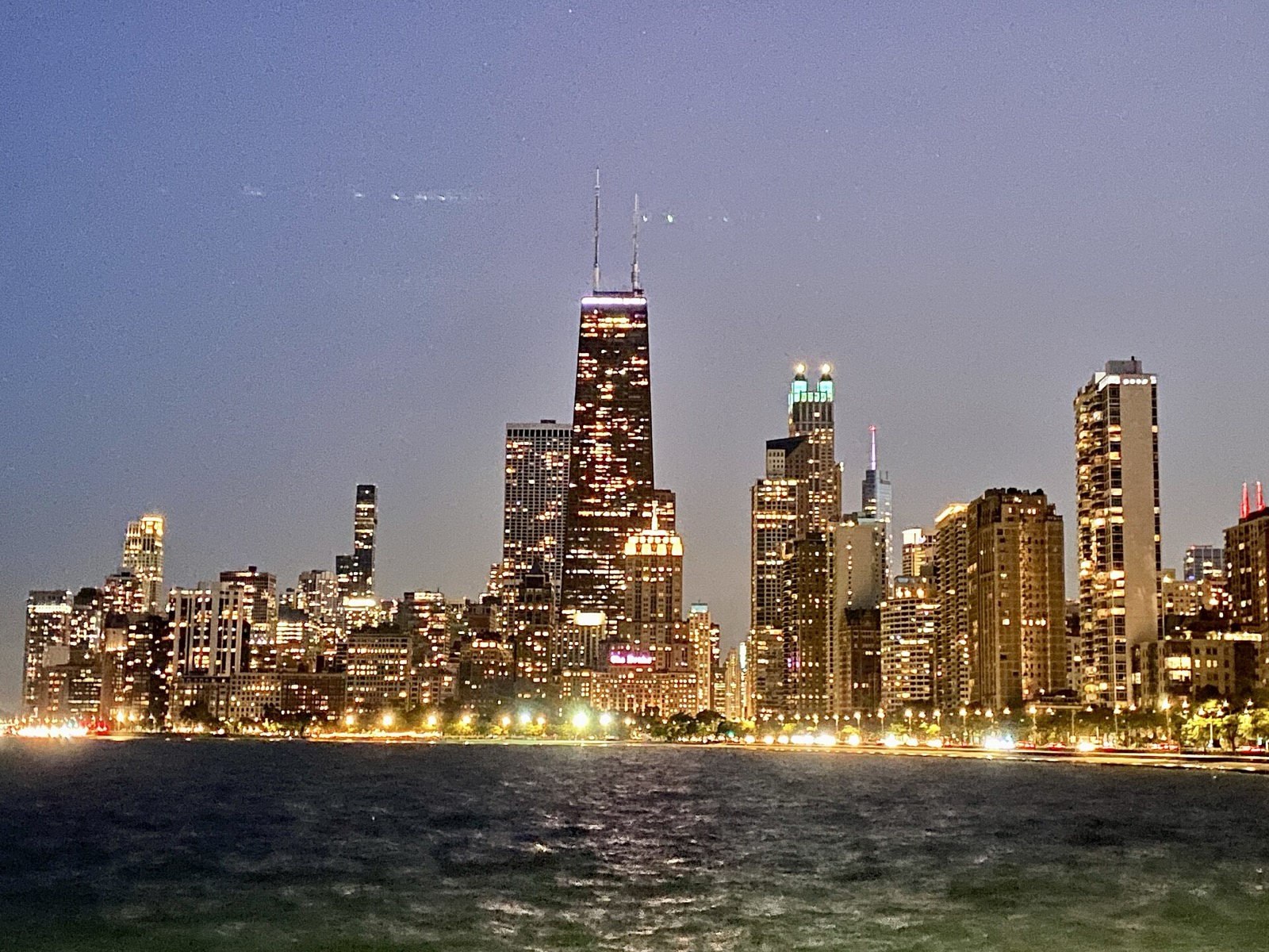 The Gold Coast skyline lit at dusk, seen across Lake Michigan from North Avenue Beach