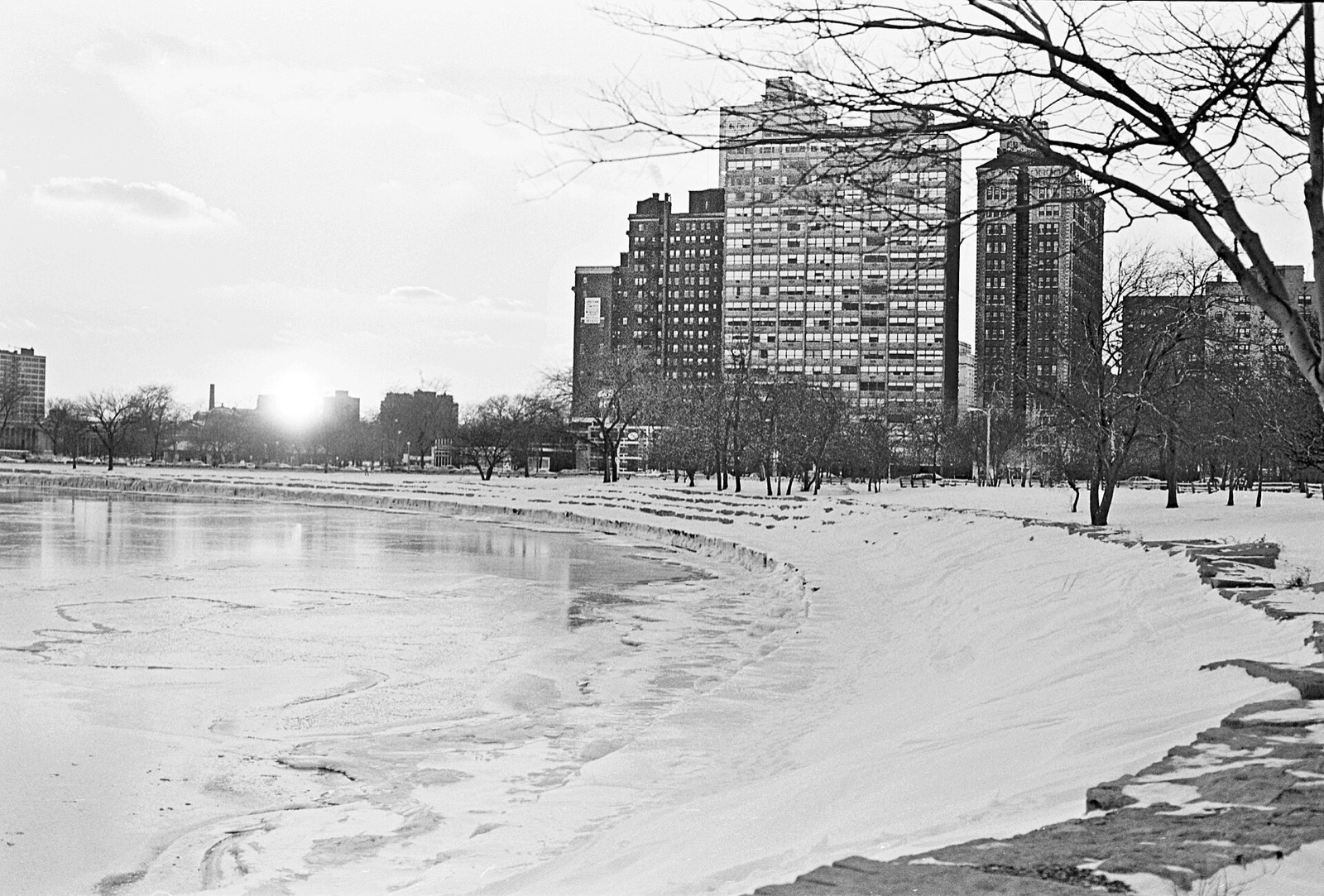 Snow-covered Hyde Park lakefront with apartment towers and a frozen lagoon, in black and white