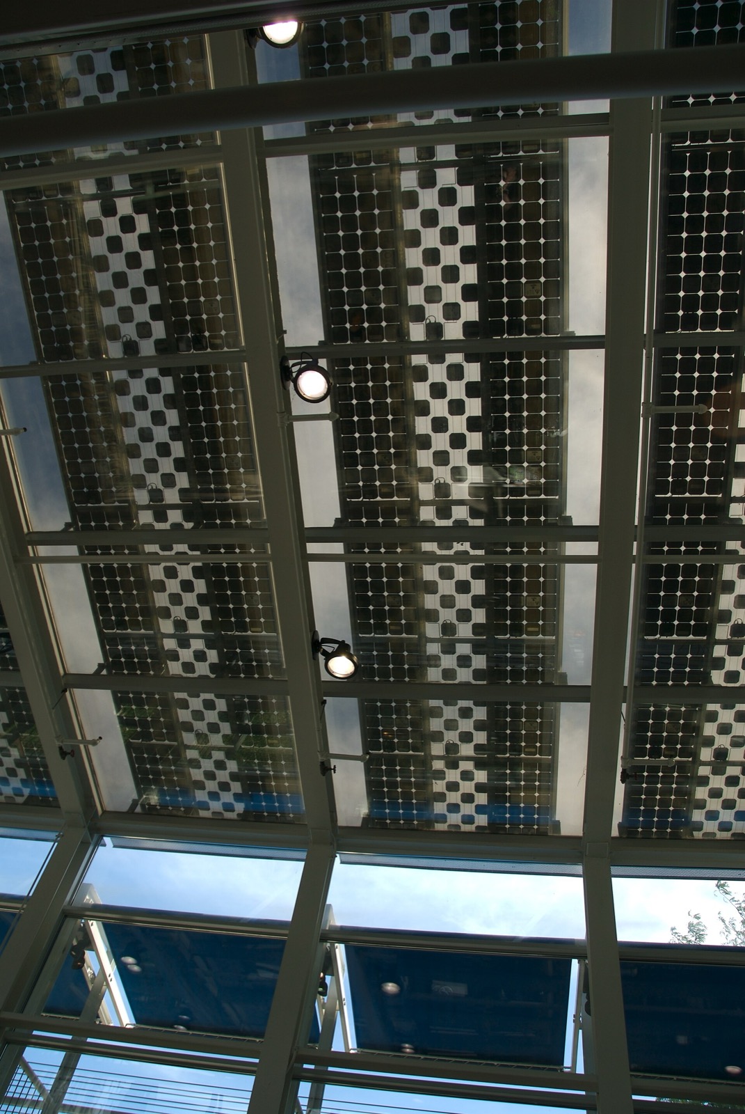 Solar panels in the sloping glass roof of the bike station atrium, seen from below
