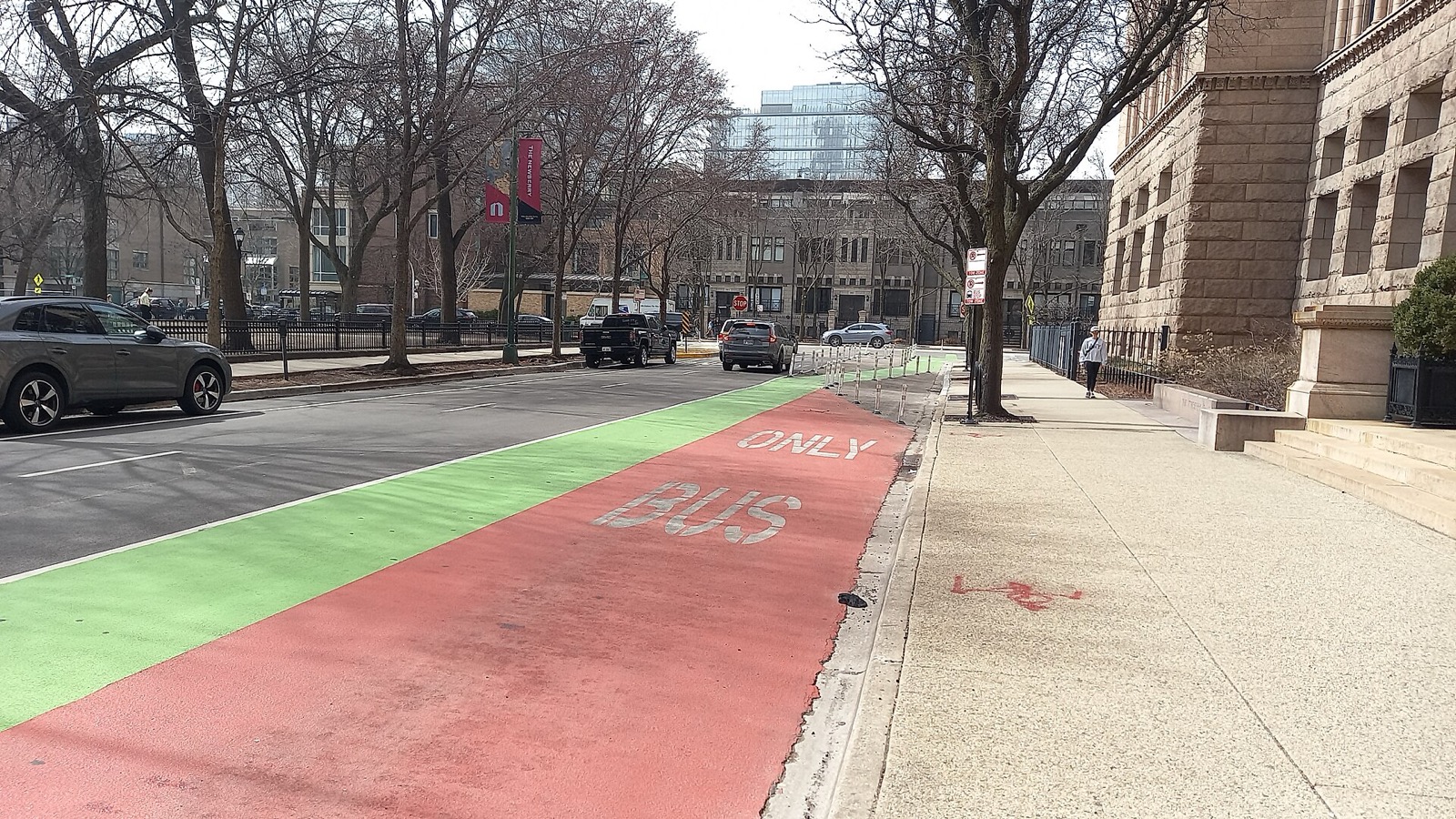 A wide Chicago sidewalk beside a red and green bus-only lane